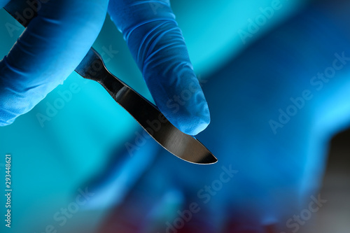 Fototapeta Surgeon arms in sterile uniform holding sharp knife while operating patient in surgical theatre closeup
