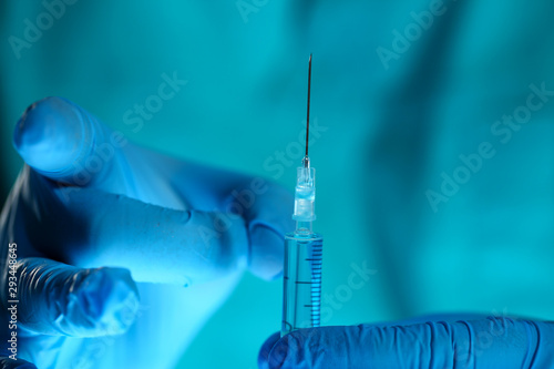 Physician injector arms in sterile uniform holding syringe while operating patient in surgical theatre closeup. HIV protection aids medication botulinum toxin innovation 911 team concept