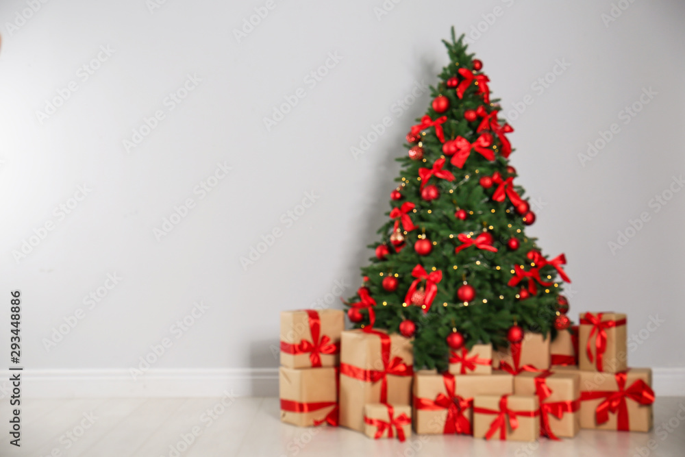 Blurred view of decorated Christmas tree and gift boxes near light wall. Space for text Blurred view of decorated Christmas tree and gift boxes near light wall. Space for text