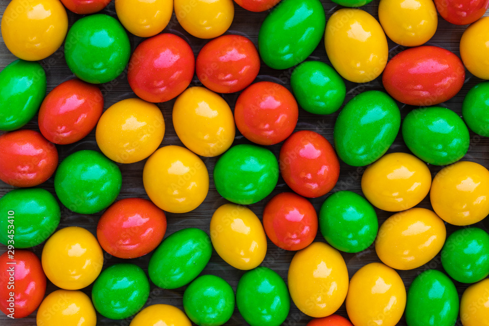 Background in the form of balls of milk chocolate coated with multi-colored glaze, top view Background in the form of balls of milk chocolate coated with multi-colored glaze, top view