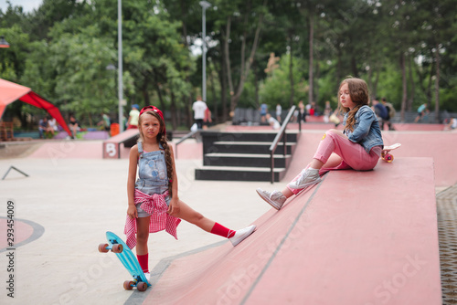 Two female skaters best friends hangout at the skate park on sunset .Laughing and fun.