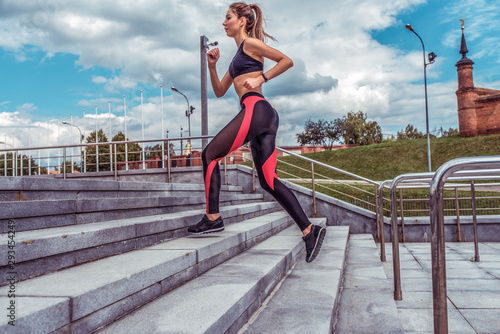 Beautiful girl athlete running on stairs in the summer in autumn and spring in the city, jogging running, sportswear, top leggings, sneakers, active fitness lifestyle, outdoor sports exercise.