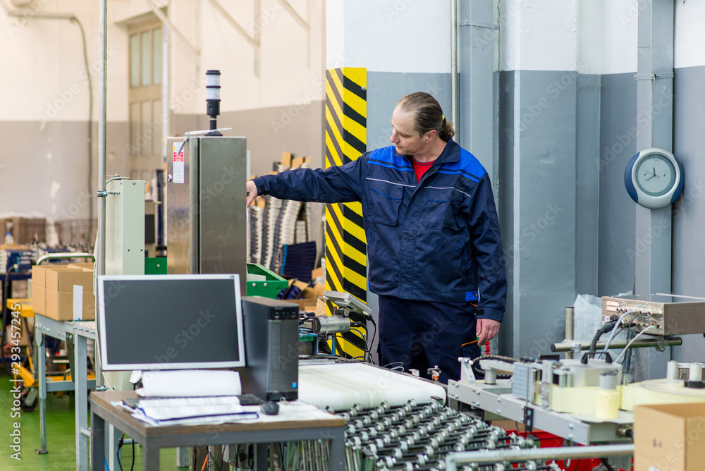 Factory worker controlling a machine in a production line Factory worker controlling a machine in a production line