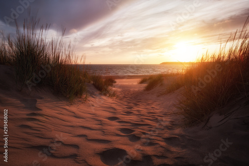 Golden sunset on the sea shore and footprints in the sand. Beautiful sand dunes.