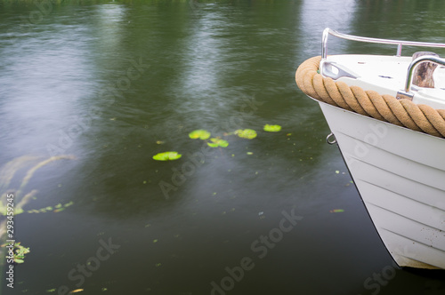 Obraz na plátne Front of stationary sloop boat in moving water, with space for text