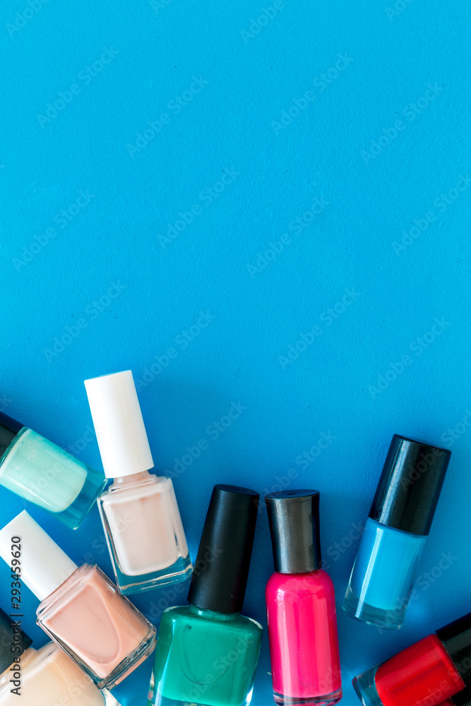 Obraz premium Choose nail polish. Polish bottels on blue background top view copy space
