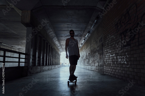 Young man with longboard in a tunnel
