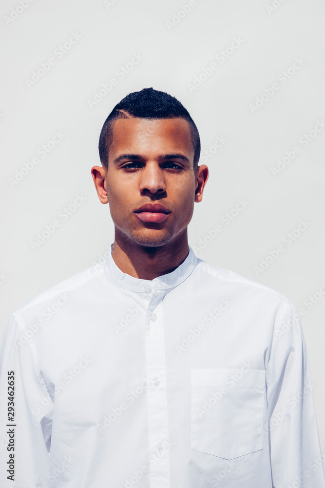 Portrait of young man with shaved hair wearing white shirt in front of white background Portrait of young man with shaved hair wearing white shirt in front of white background