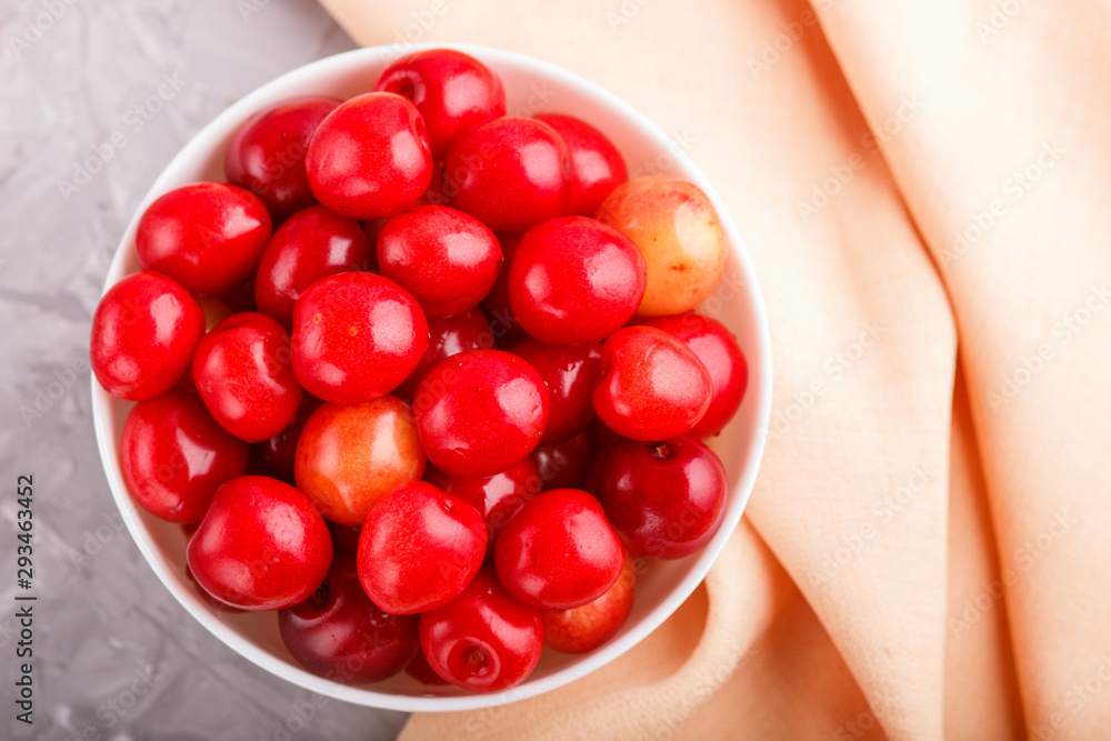 Fresh red sweet cherry in white bowl on gray and pink background. top view. Fresh red sweet cherry in white bowl on gray and pink background. top view.