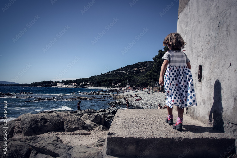 Φωτογραφία petite fille en robe se promenant au bord de la mer dans le sud de la France à S