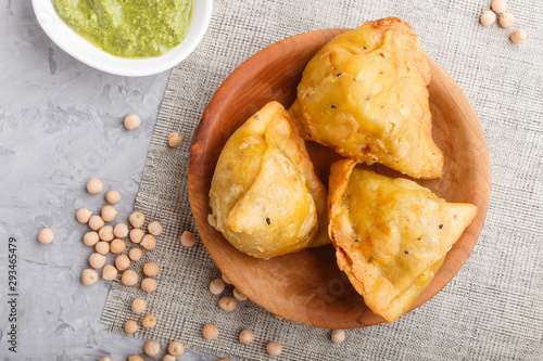 фотографія traditional indian food samosa in wooden  plate with mint chutney on a gray concrete background