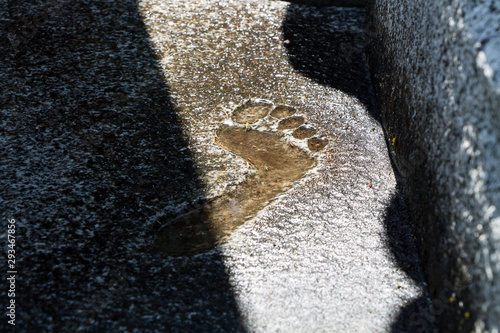 Barefoot imprint into concrete. A Footprint illuminated by sunlight
