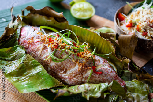Fotografie Red snapper baked in banana leaf and papaya salad