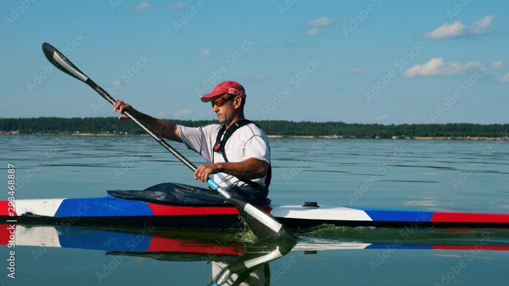 Side view of a man canoeing across the waterscape Side view of a man canoeing across the waterscape