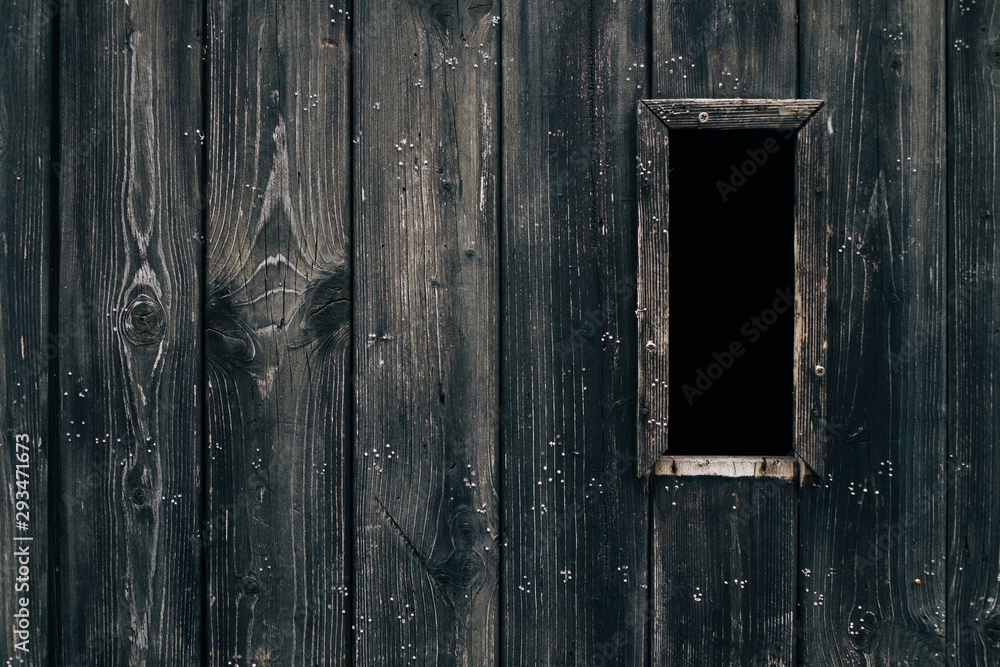 Spooky dark black vertical window in rustic brown ancient textured wood door / Halloween horror concept