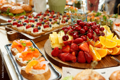Obraz na plátně Fruits, fish snacks and dessert on catering table