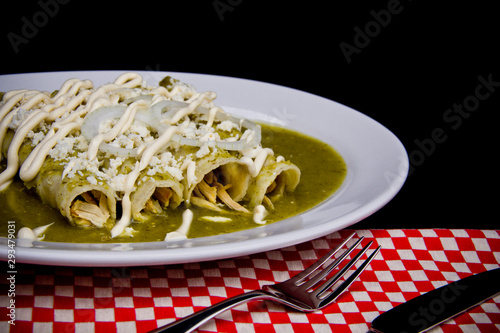 Mexican enchiladas with green sauce cheese and sour cream