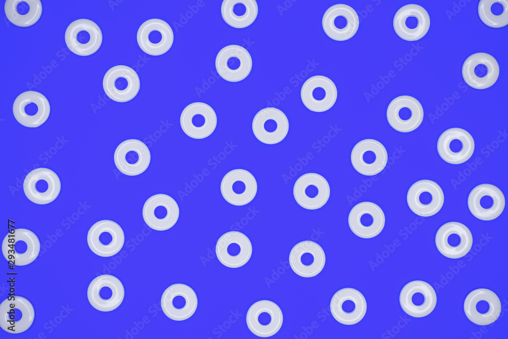 Flat round white plastic beads in irregular pattern on blue cardboard background