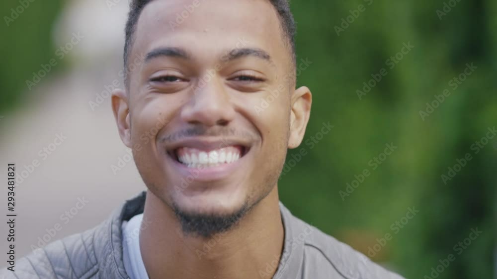 Handsome black male reacts and laughs at something as he looks to camera, in slow motion Handsome black male reacts and laughs at something as he looks to camera, in slow motion