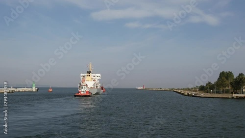 Container Cargo Ship with Auxiliary Boat goes out from port to the sea at summer day