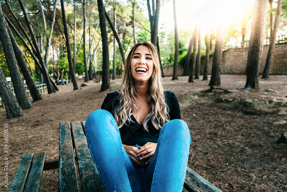 Funny laughing young woman sitting on a wooden table in a park. Funny laughing young woman sitting on a wooden table in a park.