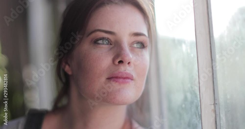 Young adult female looking out of window