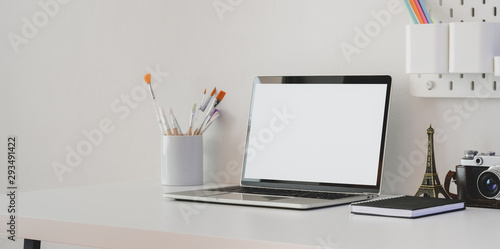 Minimal artist workspace with blank screen laptop computer with camera and decorations