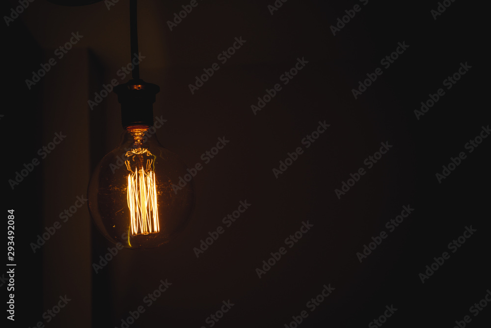 Glowing light bulb in the dark on wall and copy space for text, idea concept