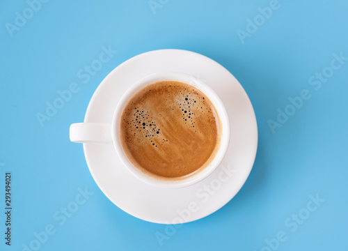Top view of hot coffee and foam in white cup isolated on blue background and copy space.Coffee menu in the coffee shop or restaurant.