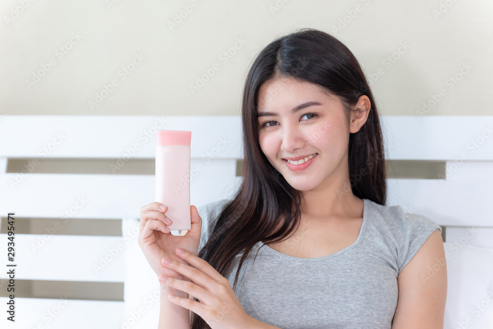 Young beautiful woman holding and skin lotion in her hand and smiling with happiness, copy space Young beautiful woman holding and skin lotion in her hand and smiling with happiness, copy space