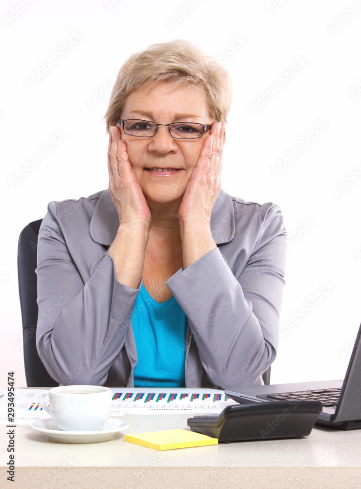 Elderly business woman analyzing financial charts at desk in office Elderly business woman analyzing financial charts at desk in office