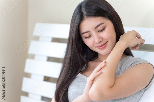 Free Download Young beautiful woman rubbing skin lotion on her arm with happily on bed at home, copy space, healthcare skin concept - GFXLoad