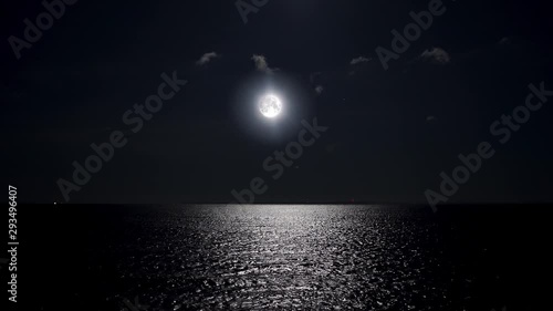 Full moon at night reflecting on the water. Alpha channel moonlight bright sea reflection. Clear big distinct moon glowing over the ocean in eerie night scene.