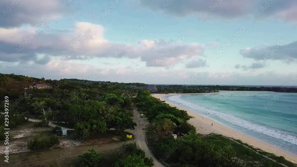 Aerial view of beachfront on pacific island with small forest and resort in background Aerial view of beachfront on pacific island with small forest and resort in background