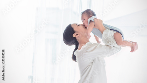 Portrait of asian mother lifting and playing with newborn baby, baby talking to mother. Health care family love together. Asian girl lifestyle. Asia mother's day concept photo