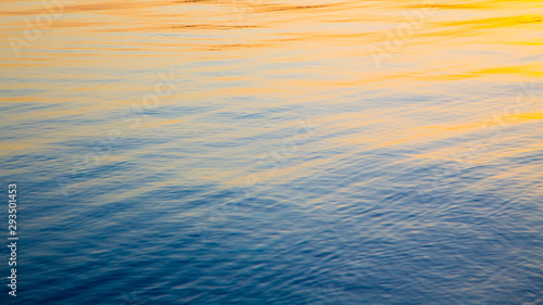 Clear water texture in blue and orange. Background of the ocean and the sea backlit by the sun. Soft waves. Natural water © Alwih