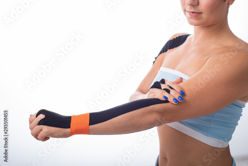 A female athlete puts a kineziotape on her wrist. Kineziology, alternative treatment for injuries of joints and tendons. Physiotherapy of chronic inflammation of the joints of a womans arm. photo