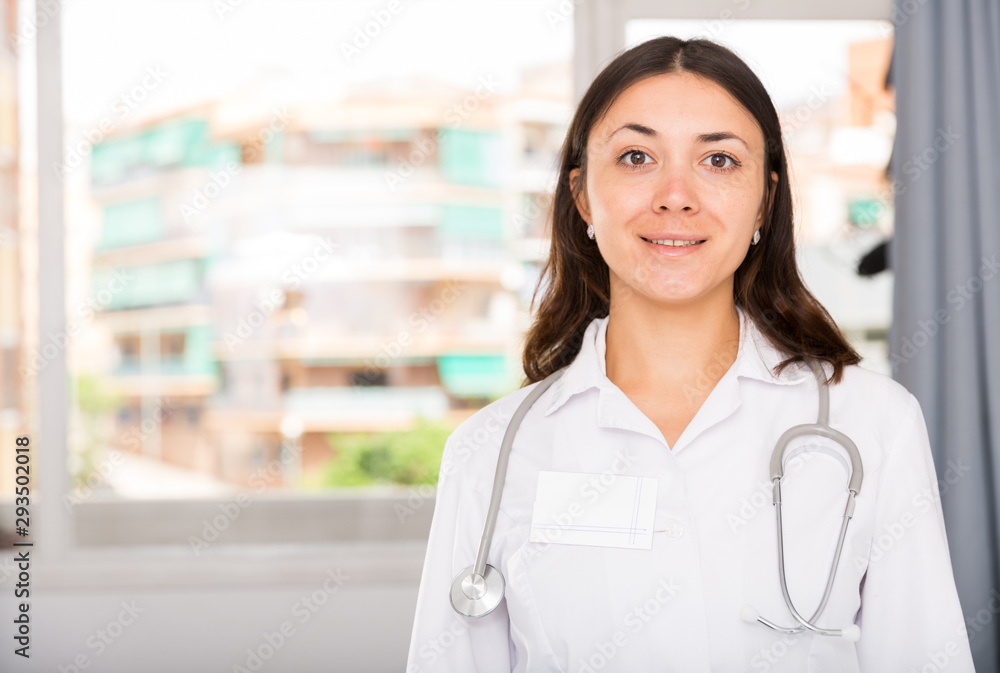 Obraz premium Young female practitioner in white uniform standing in clinic's office