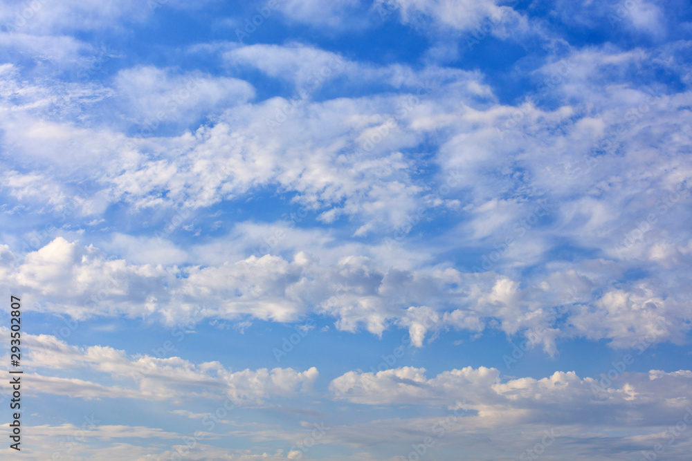 White lush clouds float in the bright saturated blue sky. White lush clouds float in the bright saturated blue sky.