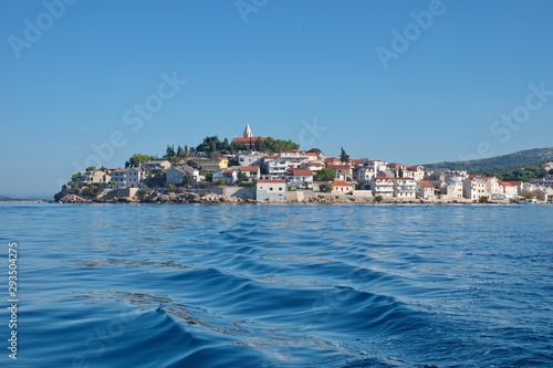 Sailing on motor boat on Adriatic sea with Primosten cityscape in the background. Vacation in Croatia
