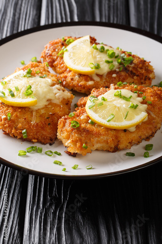 Tasty lemon romano chicken cutlet breaded close-up on a plate. vertical