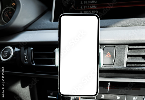 Fototapeta Naklejka Na Ścianę i Meble -  Smartphone in a car use for Navigate or GPS. Driving a car with Smartphone in holder. Mobile phone with isolated white screen. Blank empty screen. copy space. Empty space for text. modern car interior