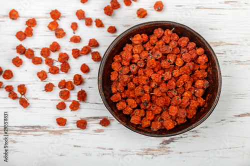 Fotografija Dried Rowan berries in a ceramic bowl on a white table