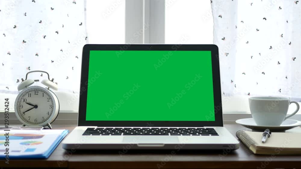 4K. laptop computer with a green screen chroma key set on work office table near the window with white curtain blow 4K. laptop computer with a green screen chroma key set on work office table near the window with white curtain blow