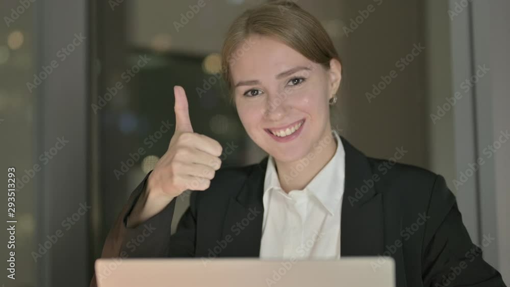 Close Up of Businesswoman showing Thumbs Up in Office at Night Close Up of Businesswoman showing Thumbs Up in Office at Night