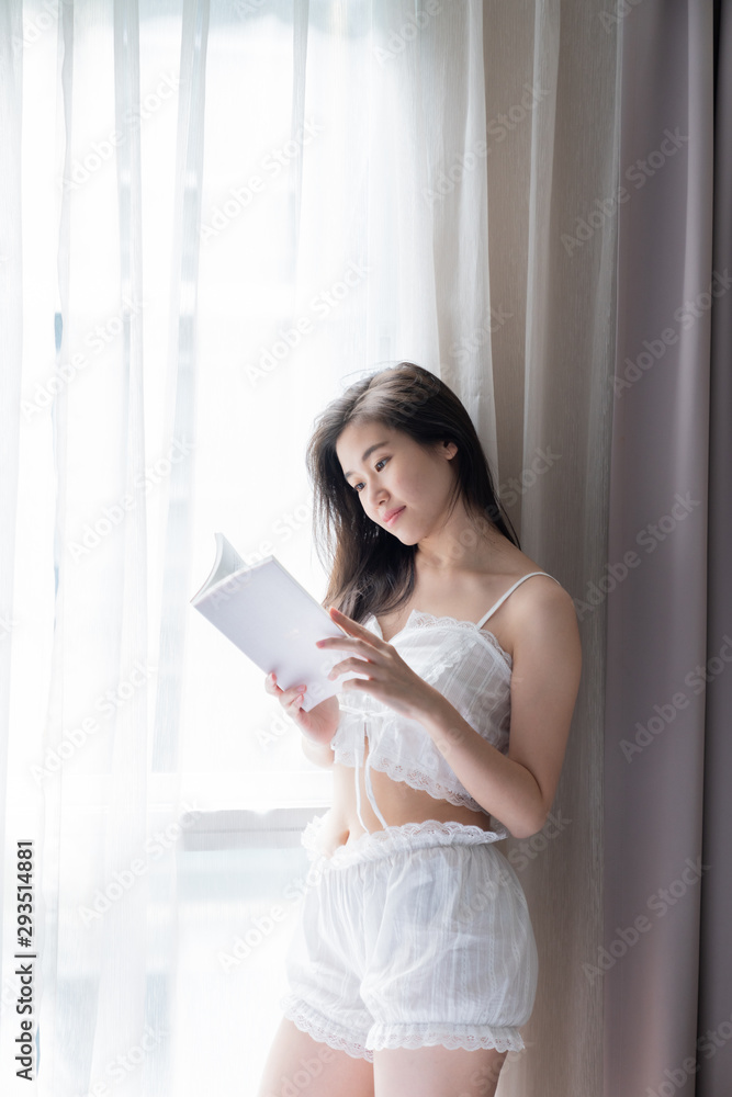 Asian women while reading book near window with shear curtain / bedroom concept / copy space Asian women while reading book near window with shear curtain / bedroom concept / copy space