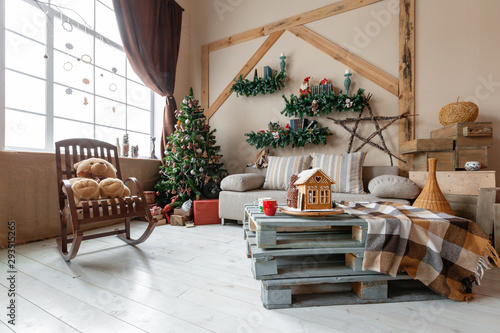Calm image of interior modern home living room decorated christmas tree and gifts, sofa, table covered with blanket.