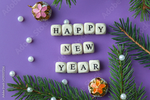 Happy New Year lettering on purple background. Christmas tree branches and beads. Image for postcards and banner.