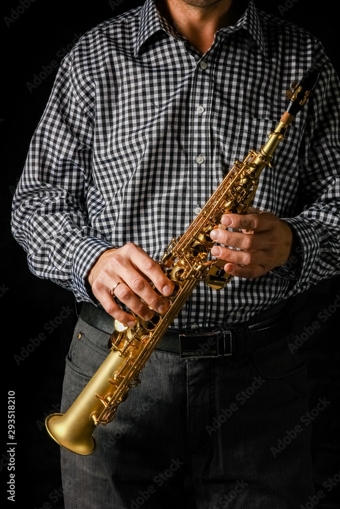 Naklejka premium soprano saxophone in hands on a black background
