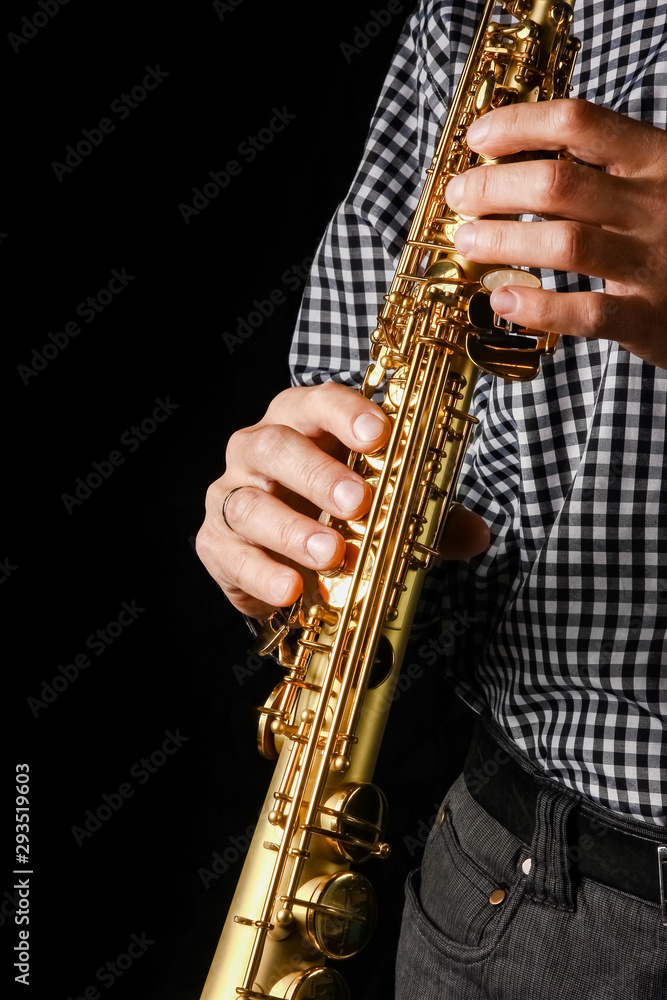 Naklejka premium soprano saxophone in hands on a black background